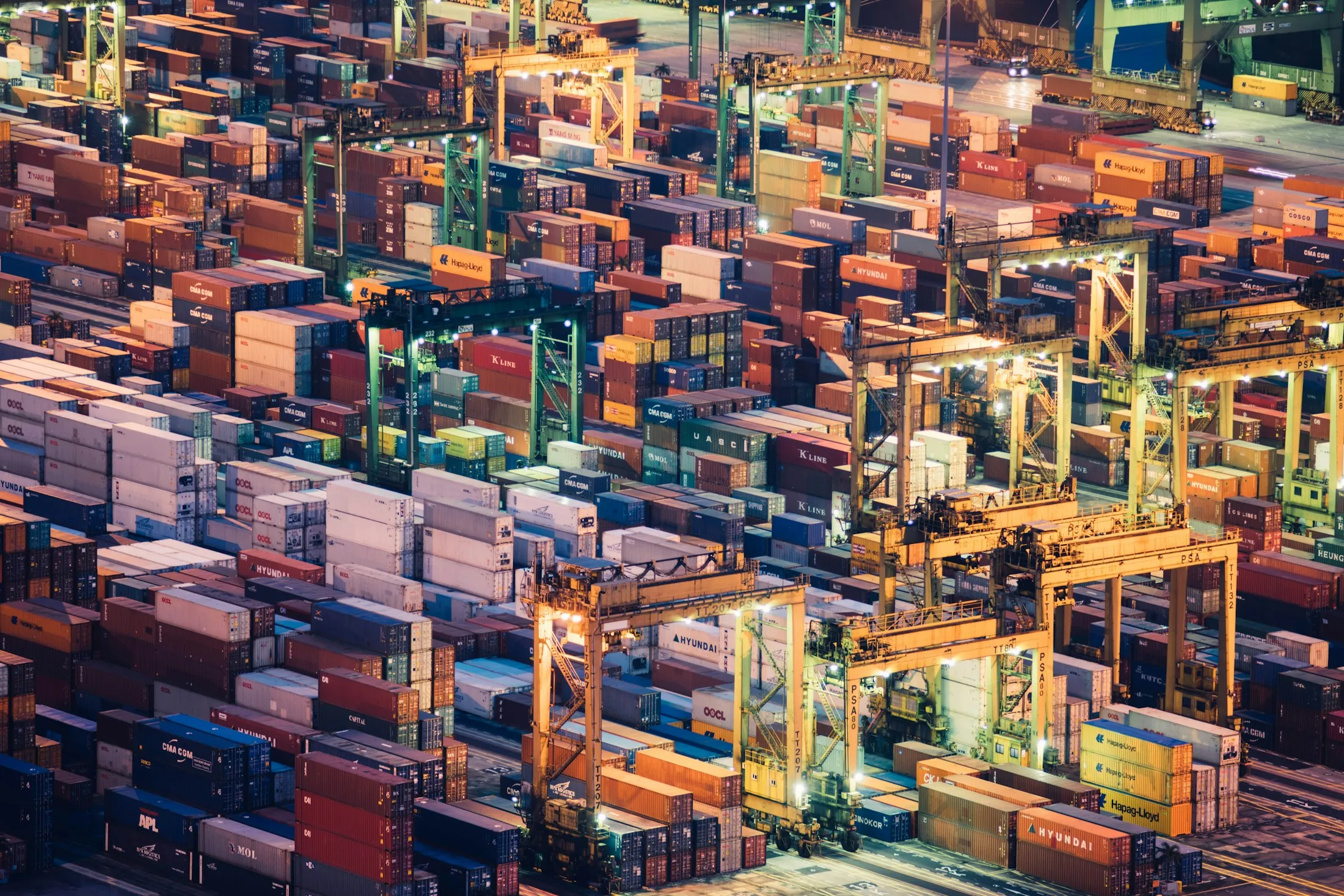 Cranes and stacked containers across a working freight terminal